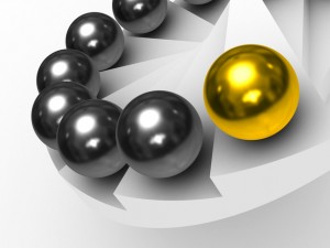 A spiral of shiny grey spheres with one prominent golden sphere standing out like a government leader from the rest, all placed on a white, geometric surface.