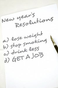 A piece of paper titled "New Year's Resolutions" lists four goals: a) lose weight, b) stop smoking, c) drink less, and d) GET A JOB. A pen is placed on the right side of the paper, ready for checking off accomplishments and interviewing notes.