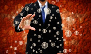 A person in a black suit and blue tie is standing against a red background. Their hand is outstretched, touching an interconnected network of circular icons, each containing small human figures, representing social or business connections and the importance of retaining talent.