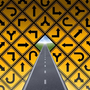A straight road leads to a bright sky in the distance, surrounded by a wall of yellow road signs depicting various directional arrows, including turns and curves. The signs create a pattern, forming a triangular opening above the road, symbolizing the journey of one's career.