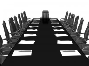 A long black conference table surrounded by black leather chairs evokes a sense of formality, as if awaiting a council meeting. Each seat has a pad of paper and a pen placed in front of it. The room is empty, and the chair at the head of the table is prominently positioned. The background is white.