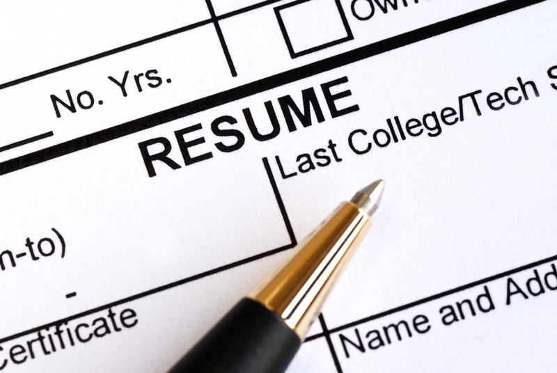 Close-up image of a resume form with a section for "Last College/Tech" and other fields. A sleek pen with a black body and gold accents is resting on the resume, poised to fill out the information.