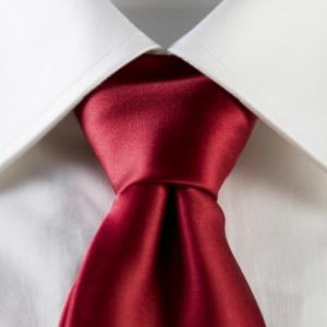 Close-up image of a neatly tied red silk tie against a crisp white dress shirt. The tie knot is symmetrical and the collar is sharp, giving a polished, professional appearance—perfect for making a strong impression at an interview.