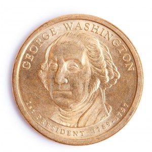 A close-up image of a gold-colored coin featuring a portrait of George Washington. The text on the coin reads "George Washington" above the portrait and "1st President 1789-1797" below, highlighting his role in the early Federal period of American history.