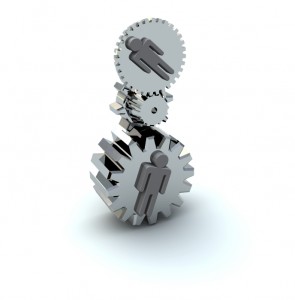 Three metallic gears interlock and stack vertically against a white background. Each gear has a human silhouette embossed on its surface, symbolizing collaboration and teamwork, embodying the core principles of a successful HR career.