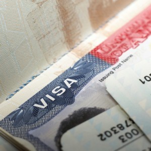 Close-up view of a visa page in a passport with partial information visible. The word "Visa" is prominently displayed, reflecting the intricacies of foreign policy, and there are some obscured details including numbers and text on the bottom right corner.