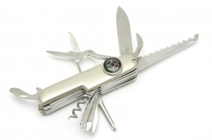 An open multi-tool pocket knife with various tools extended, including a blade, a serrated knife, scissors, a corkscrew, a bottle opener, small screwdrivers, and a compass on the handle. The tool's silver-colored body resembles the perfect resume of essential gadgets for every adventure.