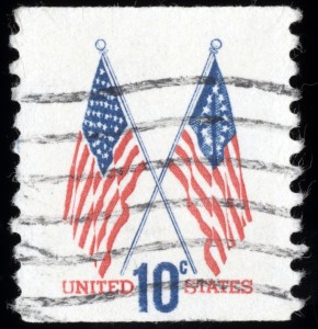 A 10-cent United States postage stamp featuring two crossed American flags. The flags are printed in red and blue ink. "UNITED STATES" is printed in red at the bottom, with "10¢" in large blue letters. The stamp, reminiscent of public-private partnerships, shows cancellation marks.