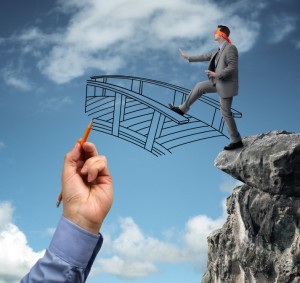 A blindfolded person in a suit walks cautiously off a cliff, seemingly guided by purpose as they step onto a hand-drawn bridge sketched by a large, disembodied hand holding an orange pencil. The sky in the background is blue with scattered clouds.