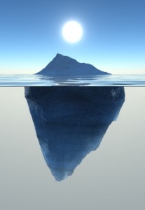 An iceberg with a visible portion above water and a much larger, hidden portion below the surface, under a clear blue sky with the sun shining brightly directly above it, symbolizes the unseen risks that lie beneath.