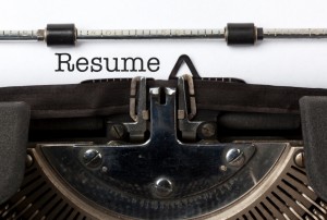 Close-up of a typewriter with the words "Objective Statement: Resume" typed on white paper. The typewriter's metallic parts and black ink ribbon are visible.