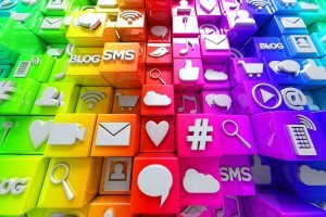 A vibrant collage of 3D colored cubes, each featuring various icons related to social media and technology. Icons include speech bubbles, magnifying glasses, shopping carts, envelopes, hearts, cameras, musical notes, user profiles, and more.