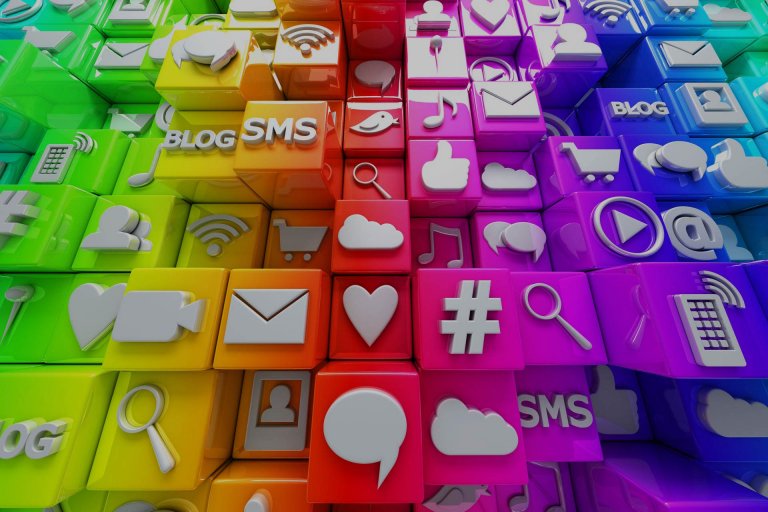 Colorful 3D blocks, each with a different social media or digital icon, including symbols for blogs, SMS, shopping carts, hearts, music notes, clouds, video players, and magnifying glasses. The blocks are arranged in a gradient from green to pink and purple.