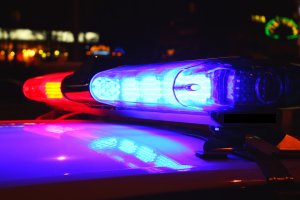 Close-up of flashing red and blue police lights atop a patrol car, illuminating the dark surroundings with a contrasting glow against the night. This poignant scene marks the end of an era as it honors a distinguished police retirement.