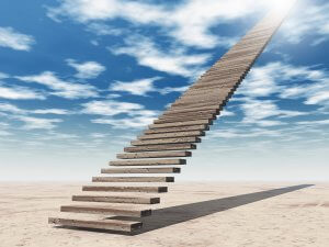 A long staircase made of wooden planks ascends into the sky, seemingly endless and disappearing into the bright sunlight above. The scene evokes an academic curiosity, set in a barren, sandy landscape under a clear, partly cloudy blue sky.