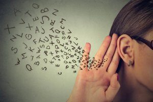A person with glasses is holding their hand to their ear, as if listening intently. A jumble of letters is flowing towards the ear, symbolizing the transmission or reception of information through listening—a crucial soft skill. The background is a neutral tone.