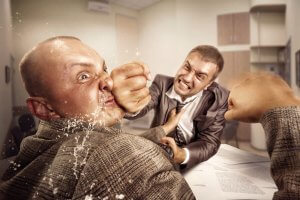 Two coworkers in business attire are in a physical altercation in an office setting. One man is landing a punch to the other's face, causing visible water-like droplets to splash out. Papers and files are scattered on the desk in the background.