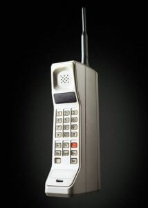 An image of a vintage, brick-style cell phone from the 1980s with a numeric keypad, a small display screen, and a tall antenna on top. Displayed against a dark background to highlight its bulky, rectangular design, it reminds us how far technology has come in aiding modern job hunting.