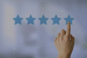 A hand is pointing to the fifth star in a row of five blue stars against a blurry, abstract background. The stars are arranged horizontally, indicating a five-star rating system for exceptional customer service.