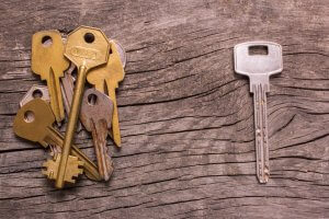 A group of brass keys on the left side of a wooden surface, with a single silver key lying separately on the right. The weathered texture of the wood provides a rustic backdrop, subtly reminding us that even in simplicity, there's an underlying need for information governance.