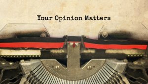 Close-up of an old-fashioned typewriter with a sheet of paper that reads "Your Opinion Matters" in typed text. The image highlights the typewriter's typebars and part of the ribbon, emphasizing the importance of feedback and our shared values of expression.