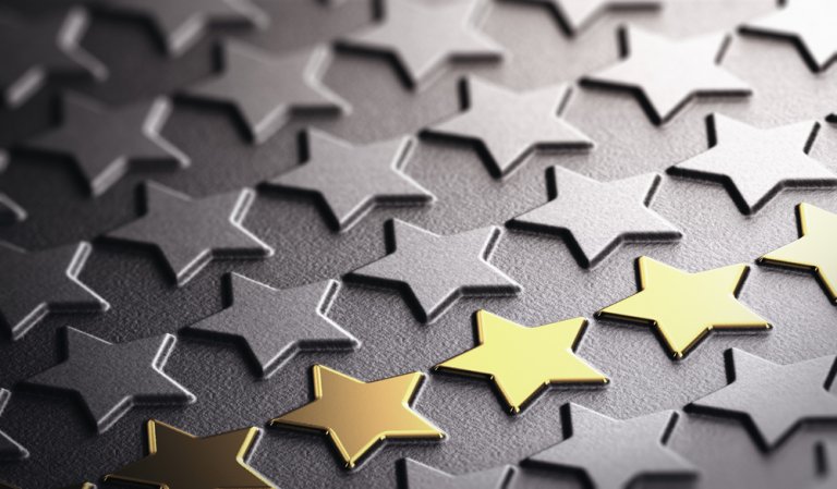 A close-up image displays rows of star shapes on a textured surface. Most of the stars are silver, with one row of gold stars standing out prominently in the foreground, lending a sense of credibility to the metallic contrast.