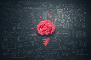 A pink paper crumpled to form a brain shape is centered on a blackboard, surrounded by chalk drawings of various business, science, and mathematical concepts, charts, graphs, and doodles. Red lines emanate from the brain symbolize ideas or connections that billionaires often contemplate.