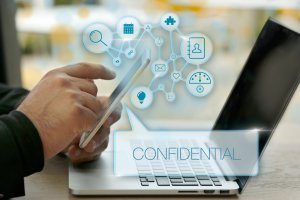 A person uses a smartphone in front of an open laptop. Icons representing various digital processes and functions float above the devices, including a calendar, email, and a lock symbol—emphasizing information governance. The text "CONFIDENTIAL" appears prominently in the foreground.