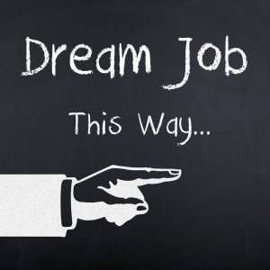 A chalkboard sign reads "Dream Job This Way..." with a hand-drawn white hand pointing to the right, evoking a sense of an exciting job search. The background is dark, simulating a blackboard.