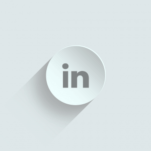 A circular icon with a light gray background and the LinkedIn logo in the center. The logo consists of the letters "in" in a darker gray. The LinkedIn icon has a subtle shadow on the lower left, giving it a slight three-dimensional appearance.