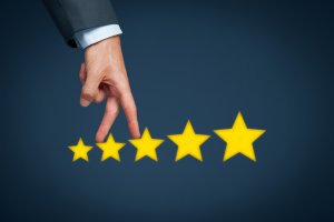 A hand in a suit indicating a 5-star rating, with fingers stretched above the stars, suggests high quality often attributed to good managers. The background is dark blue, and the stars are aligned in a row from smallest to largest.