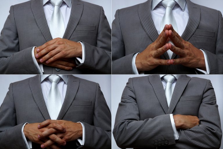 A person in a gray pinstripe suit and white tie is shown from the shoulders down in four images. Each image depicts different hand gestures, revealing body language cues like hands clasped together, fingers forming a triangle, hands crossed, and hands resting on opposite arms.