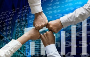 Four people form a fist bump, symbolizing teamwork and unity led by a strong leader. The background features a digital collage of financial data with numbers and graphs, suggesting a business or financial context.