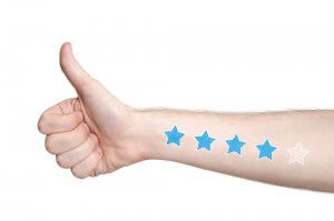 A close-up of a person's arm extended with a thumbs-up gesture. The arm has four colored-in blue stars and one white outlined star on it, symbolizing a four out of five stars rating often given to good managers. The background is white.