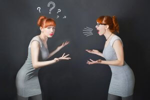 A woman with red hair is depicted twice; the left version looks confused with drawn question marks above her head, as if pondering "Tell Me About Yourself," while the right version appears to be angrily shouting with drawn sound lines emanating from her mouth. Both are wearing grey dresses against a dark background.