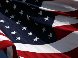 Close-up of an American flag waving in the wind. The flag, with its red and white stripes and white stars on a blue field, symbolizes the 50 states of the United States—a nation built on values that drive a strong job market.