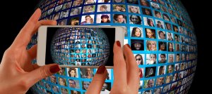 Hands holding a smartphone in front of a spherical collage of many small photos of diverse individuals, capturing an image of the collage on the screen. This vibrant mosaic seems to represent hundreds of faces, each with their own unique career journey.