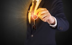 A person in a suit holds a key attached to a keychain shaped like a house. The image has a glowing light effect emanating from the key, creating a bright and dynamic visual focus on the key and keychain, symbolizing government-secured housing initiatives.