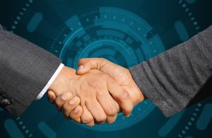 Two individuals in business attire shaking hands against a futuristic technological background with circular digital patterns, signifying the successful outcome of a job interview or business partnership.