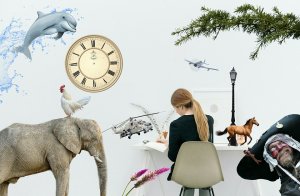 A woman sits at a desk with her back facing the viewer. Surrounding her are surreal elements, embodying a sense of authenticity: a dolphin, an elephant, a chicken, a vintage clock, a helicopter, a toy horse, a street lamp, and even a man dressed as a pirate—all against a white background.