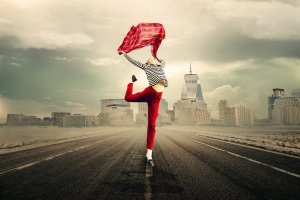 A person dressed in a striped shirt, red pants, and black shoes leaps joyfully on an empty road, seemingly escaping the burnout of everyday life. They hold a red scarf, which flows in the air. The background features a city skyline under a cloudy sky.