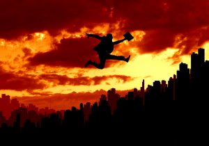 Silhouette of a person in a suit jumping over a city skyline at sunset, with a vibrant red and orange sky in the background. The person is holding a briefcase and appears to be in mid-leap, symbolizing ambition and overcoming job-related obstacles.
