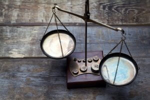 An old-fashioned balance scale with two round metal pans, chained to a central beam, sits on a rustic wooden surface. The worn base and neatly arranged weights evoke antiquity and tradition, symbolizing a timeless value proposition.