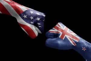 Two fists are shown against a black background. The fist on the left is painted with the flag of the United States, while the fist on the right is painted with the flag of New Zealand. Positioned as if about to bump each other, they symbolize strong relationships between nations.