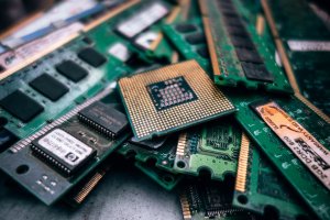 A close-up view of a scattered pile of computer hardware components, mainly RAM sticks and a central processing unit (CPU) with visible gold pins. The information-rich components are arranged in a somewhat cluttered manner, with various chips and circuits exposed.