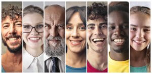 A collage of seven diverse people is shown, each smiling and appearing in a vertical strip. The individuals vary in age, gender, and ethnicity, effectively communicating a wide range of human diversity.