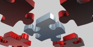 Floating puzzle pieces with shiny surfaces in hues of red and silver are depicted against a neutral background. The central piece is silver and appears to be fitting into an open space surrounded by the red pieces, suggesting a sense of completion or collaboration, much like education bringing everything together.
