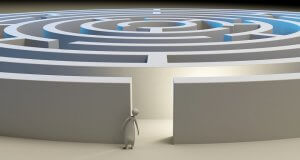 A 3D-rendered figure stands at the entrance of a large, intricate circular maze with high walls, appearing to contemplate the complex pathways ahead. With a resume of precision and thoughtfulness, the image exudes a serene yet challenging atmosphere.