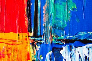 A vibrant abstract painting featuring bold, textured brushstrokes in bright red, yellow, blue, and green. The colors blend and contrast with each other like the diverse range of soft skills in a dynamic team, creating an energetic and harmonious composition.