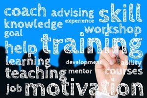 A person, much like a captain guiding their crew, is holding a marker and writing on a clear surface. Various words related to education and personal development, including "training," "motivation," "learning," "teaching," "coach," and "workshop," appear in white text against a blue background.